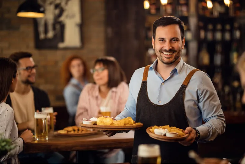Empleado de restaurante atendiendo a clientes dentro de un establecimiento.