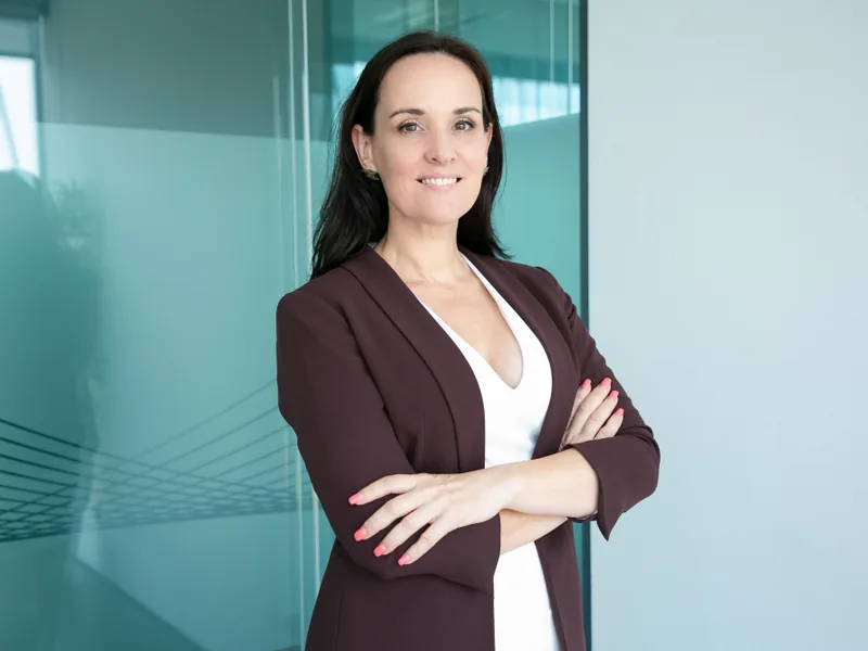 Profesional especializada posa con los brazos cruzados en una oficina moderna.